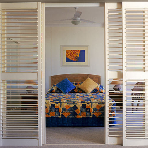 An image of a bedroom framed by timber shutter blinds in Canberra