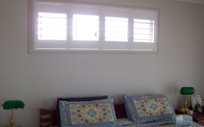 Closeup of light filtering through timber shutters into a bedroom